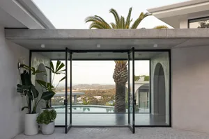 A modern residential exterior with concrete and glass elements featuring a pool and scenic view.
