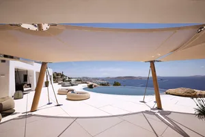 A modern residential patio featuring concrete flooring, a circular seating area, an infinity pool, and scenic ocean views.