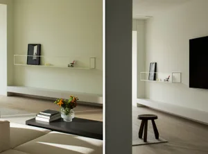 A minimalist living room featuring a sleek, low-profile white entertainment center with a TV and floating shelves, a dark woo