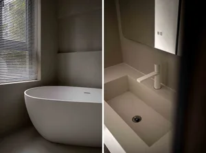 Modern minimalist bathroom with a concrete bathtub and sink, featuring a window with blinds.