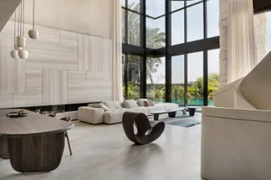 Contemporary living room featuring white furniture and large windows overlooking a landscaped outdoor area.