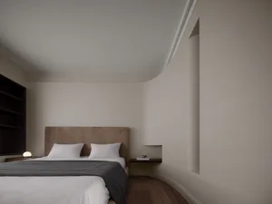 A modern minimalist bedroom with neutral-colored walls, bed, and bedding.