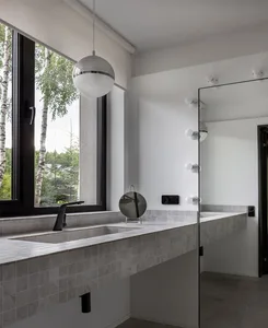 Modern bathroom interior with tiles and marble accents, featuring a large window with a view of trees.