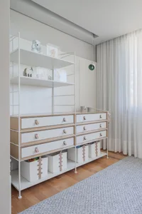 Minimalist bedroom with white furniture, wooden floors, and a gray rug.