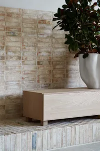 A minimalist interior with a wooden cabinet and brick wall.