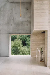 Minimalist concrete interior with a pendant light and a glass dome featuring a bird.