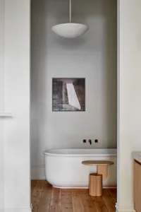 Modern bathroom featuring a minimalist concrete bathtub with wood accents and a unique lighting fixture.