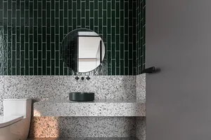 Modern bathroom with black terrazzo countertops and green tile wall