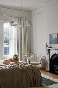 A modern bedroom with a bright and airy atmosphere, featuring a neutral color palette, a comfortable bed, and a cozy fireplac