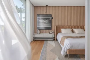 Modern minimalist bedroom with wood accent wall, white bedding, and large windows.