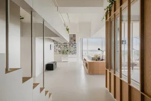 Spacious minimalist living room with white walls, wooden finishes, and natural light.