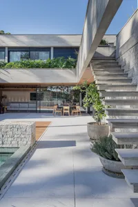 A modern patio featuring concrete flooring and a central staircase with green plants.