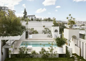 Modern exterior view of a residential home with a concrete pool and garden.