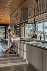 A modern residential kitchen with white cabinets, a gas stove, and a large window overlooking a scenic view.