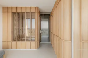 A spacious living room with wooden paneled walls, large windows, and a white floor.