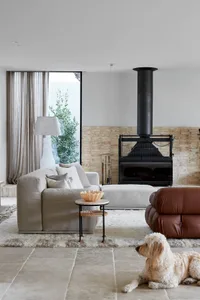 A minimalist living room featuring a grey sofa, modern fireplace, and wooden flooring.