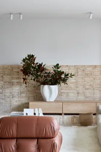 A modern living room with concrete walls, wooden furniture, and leather accents.