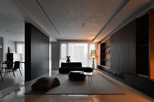 Modern living room interior with concrete flooring, leather sofa, metal coffee table, and wooden shelving.