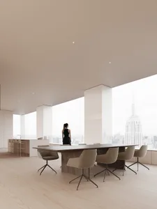 A modern office space featuring a large table with wooden chairs and a glass partition.