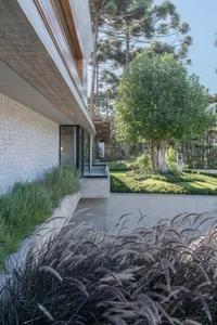A modern residential exterior featuring concrete, glass, and metal materials.