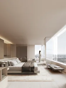 Spacious minimalist bedroom overlooking a cityscape, featuring a large bed with a grey blanket, light wooden furniture, and a