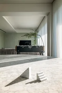 A minimalist interior design featuring marble surfaces and a table with abstract sculptures.