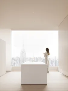 A minimalist kitchen with a white marble kitchen island and floor-to-ceiling window showing a cityscape.