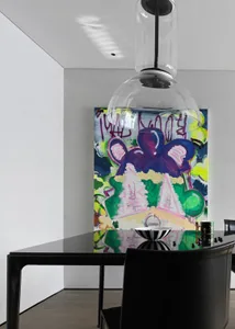 Modern art deco interior design featuring a graffiti-style abstract painting on a wall, a sleek black dining table, and conte
