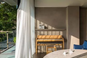A modern living room featuring a wooden piano, white curtains, and a marble dining table.