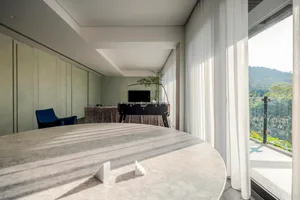 Minimalist living room featuring a white marble table and a panoramic view of mountains.