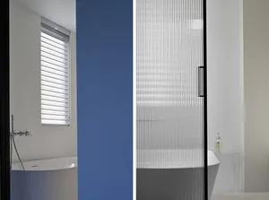 A modern bathroom featuring a glass partition and blue accent wall