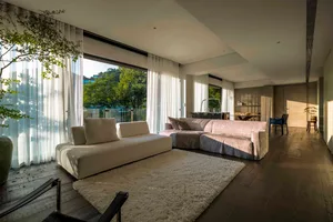 A modern living room featuring a white fabric sofa, a glass coffee table, and wooden flooring.
