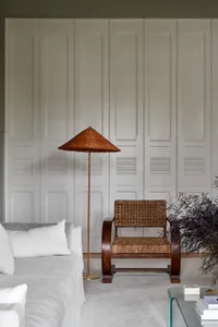 Modern living room featuring a white sofa with textured walls, a woven armchair, and a tall wicker lamp.
