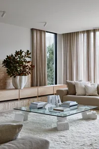 Modern living room featuring wooden furniture, a white coffee table, and a white vase with green foliage.
