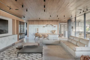 A modern living room with wooden ceiling, marble walls, and a leather sofa.