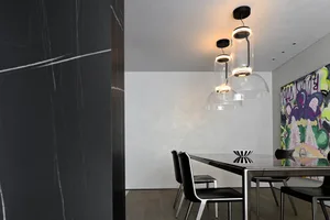 Modern minimalist dining room with black glass table and contemporary black chairs.