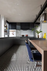Modern kitchen interior with black and white concrete walls and floor, featuring minimalist design and sleek black cabinetry.