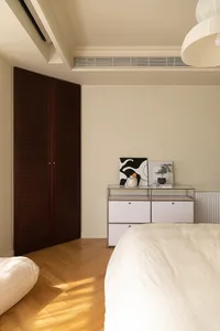 A minimalist bedroom with white furniture and a wooden floor.