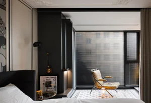 A modern bedroom featuring black accent walls and a comfortable seating area by the window.