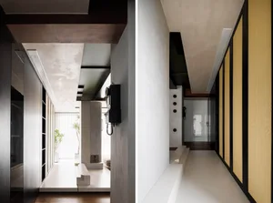 A modern interior hallway featuring textured concrete walls and floors, light fixtures, and functional design elements such a