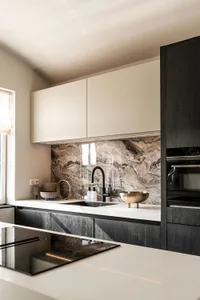 Modern residential kitchen featuring marble countertops and backsplash.