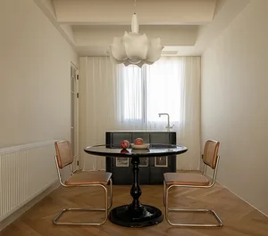 Modern minimalist dining room with black table and leather chairs, glass pendant light, and herringbone wood flooring.