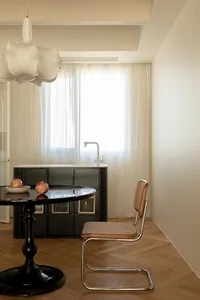 A modern minimalist office space with a sleek black table and a stylish chair with a woven backrest.