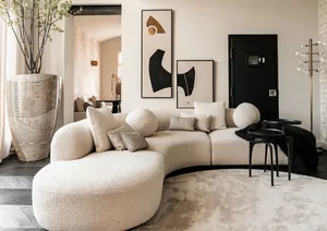 A modern, simple sofa with white velvet upholstery and spherical cushions in a living room setting.