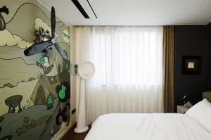 A bedroom with a white bed featuring graphic borders against a bold background.