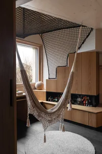 An industrial-style home office with a hammock suspended from the ceiling, featuring wood materials and a cozy workspace.