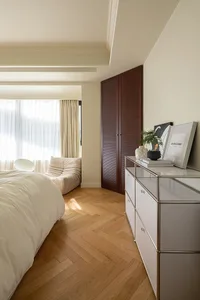 A minimalist bedroom with white furniture and wood flooring.
