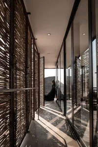 Interior view of a minimalist space featuring woven panels, glass, and metal elements.