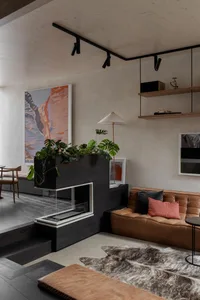 Modern minimalist living room featuring a brown leather sofa, metal floor lamp, wood fireplace, and black and white shelves.