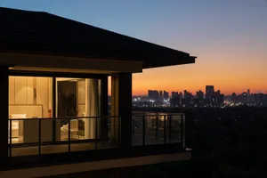 A beautifully designed modern residential balcony overlooking a cityscape at dusk.